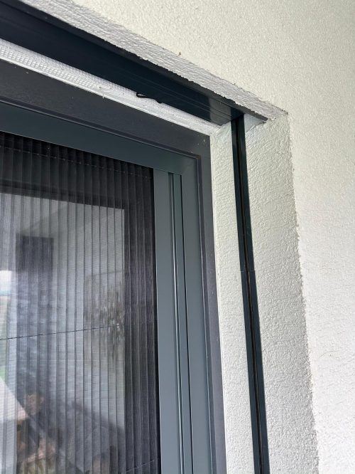 Detail okna s tmavou hliníkovou rámovou konštrukciou.